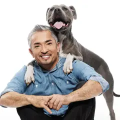 Cesar Millan, znany psi behawiorysta, z psem opartym o jego ramiona.