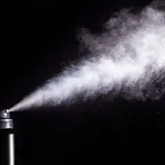 Chmura białego pyłu wydobywa się z czarnego aerozolu. Czy gaz pieprzowy działa na psy? To pytanie budzi kontrowersje.